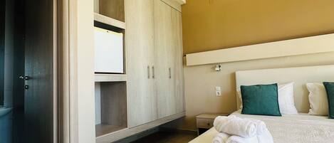 A hotel room with a bed, a wardrobe, a small table, and a wall-mounted air conditioner.