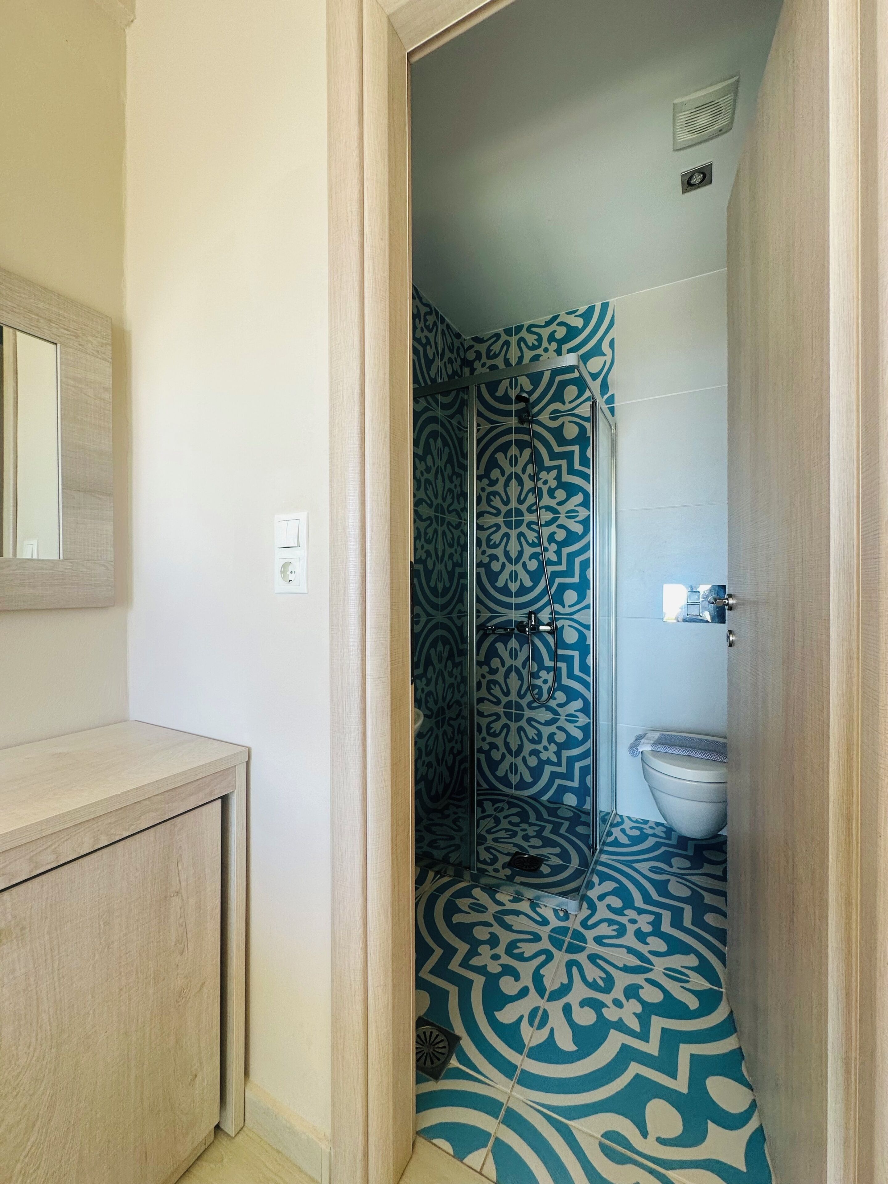 A bathroom with a patterned floor, a shower, and a toilet.