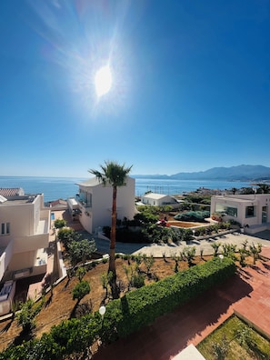 Ein Wohngebiet mit modernen Gebäuden, einer Palme und Blick auf das Meer.