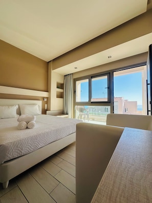 Habitación de hotel con cama, una silla, una mesa y un balcón con vistas.