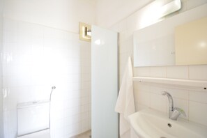 A bathroom with a shower, a sink, and a mirror.