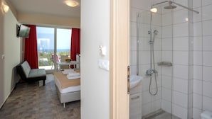 A hotel room with a bed, a desk, a shower, and a view of the outdoors. - Bellino Apartments - Adults Only (Hersonissos)