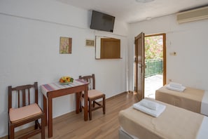 A room with a wooden table, two chairs, a television mounted on the wall, and a bed with a towel. - Bellino Apartments - Adults Only (Hersonissos)