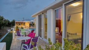 An outdoor patio area with tables and chairs, a pool, and a building with large windows. - Bellino Apartments - Adults Only (Hersonissos)