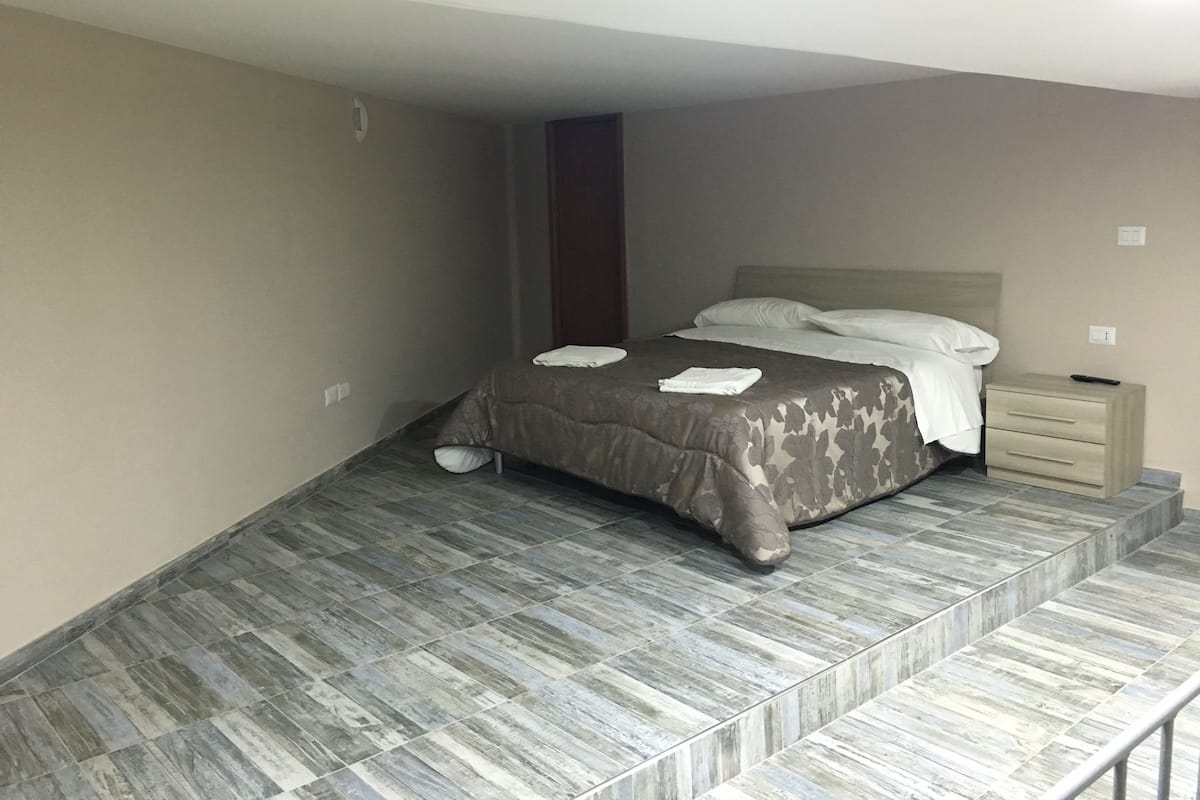 A bedroom with a bed, a nightstand, and a built-in bench.