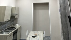 A compact kitchen with a dining area, including a table with chairs, a small sink, and a stove. - B&B Chez Moi (Naples)