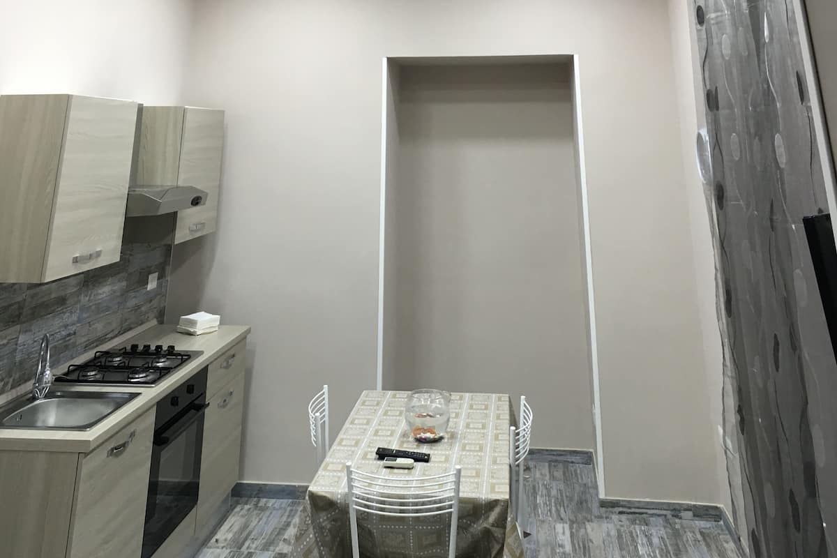 A compact kitchen with a dining area, including a table with chairs, a small sink, and a stove.