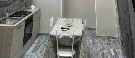 A compact kitchen with a dining area, including a table with chairs, a small sink, and a stove.