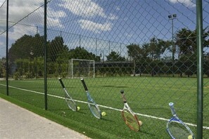 A tennis court with a chain-link fence, a goal post, and tennis rackets leaning against the fence. - Fruit Village Torre dell'Orso La Brunese (Melendugno)