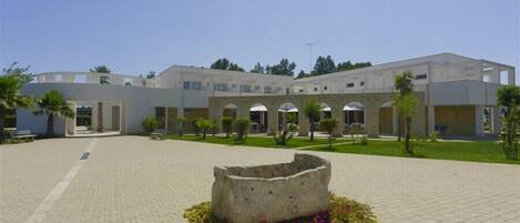 A modern building with a courtyard, featuring a central stone structure surrounded by colorful flowers.