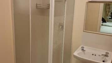Une salle de bain avec une douche à parois de verre, un lavabo et un miroir au-dessus.