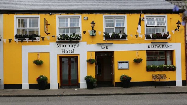 Um edifício amarelo com uma placa indicando o Hotel Murphy, um bar e um restaurante.