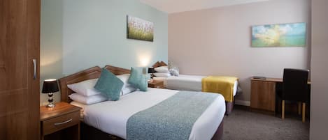 Habitación de hotel con dos camas, un escritorio y una silla.