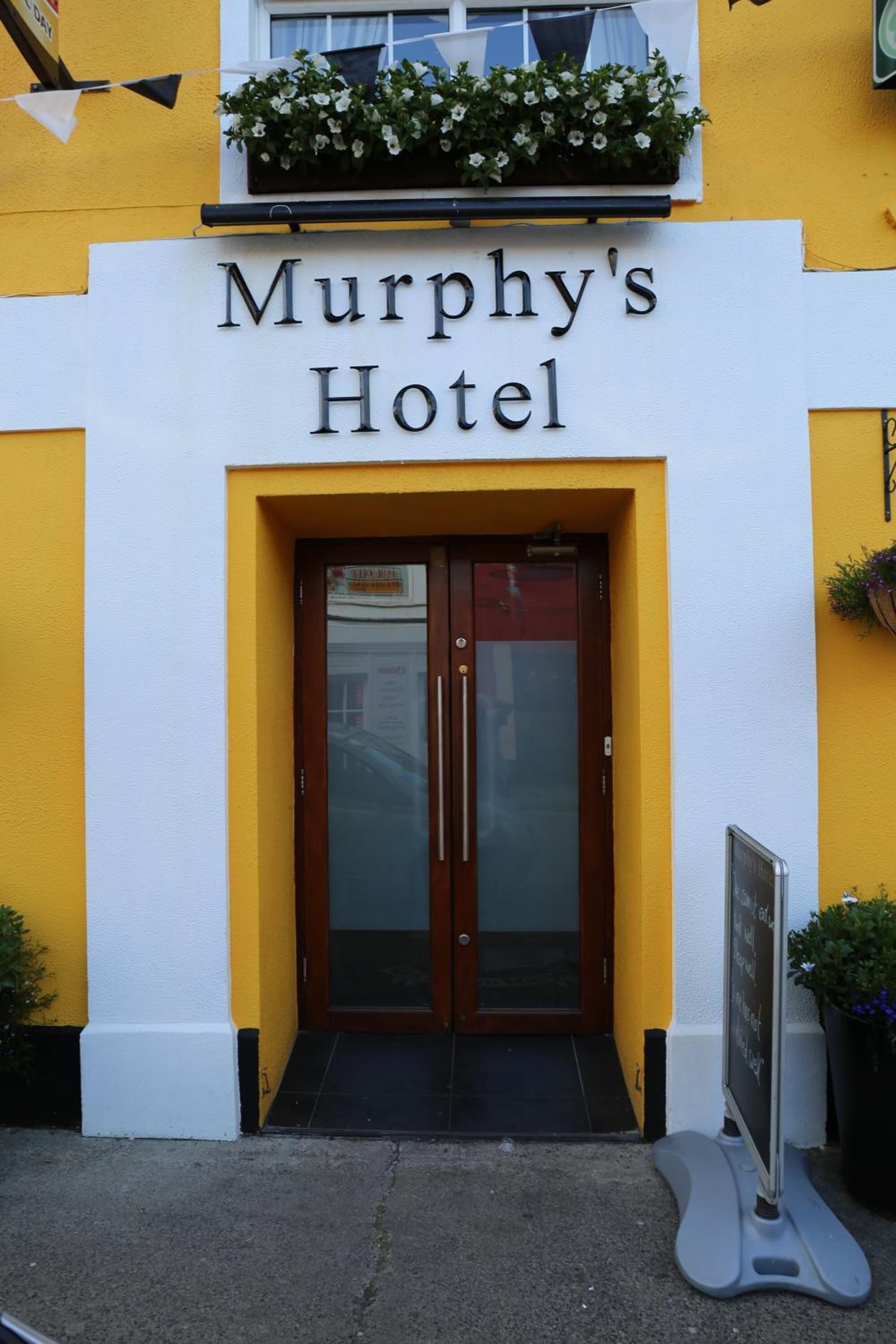 Hotel Murphy's, con fachada amarilla, puerta doble de madera y una pequeña ventana sobre la entrada.