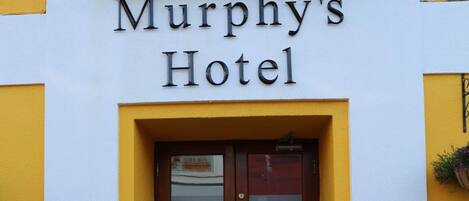 Murphy's Hotel with a yellow facade, a wooden double door, and a small window above the entrance.