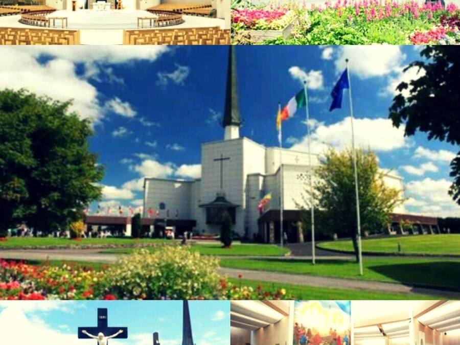 A church with a cross, flags, and a clear blue sky.
