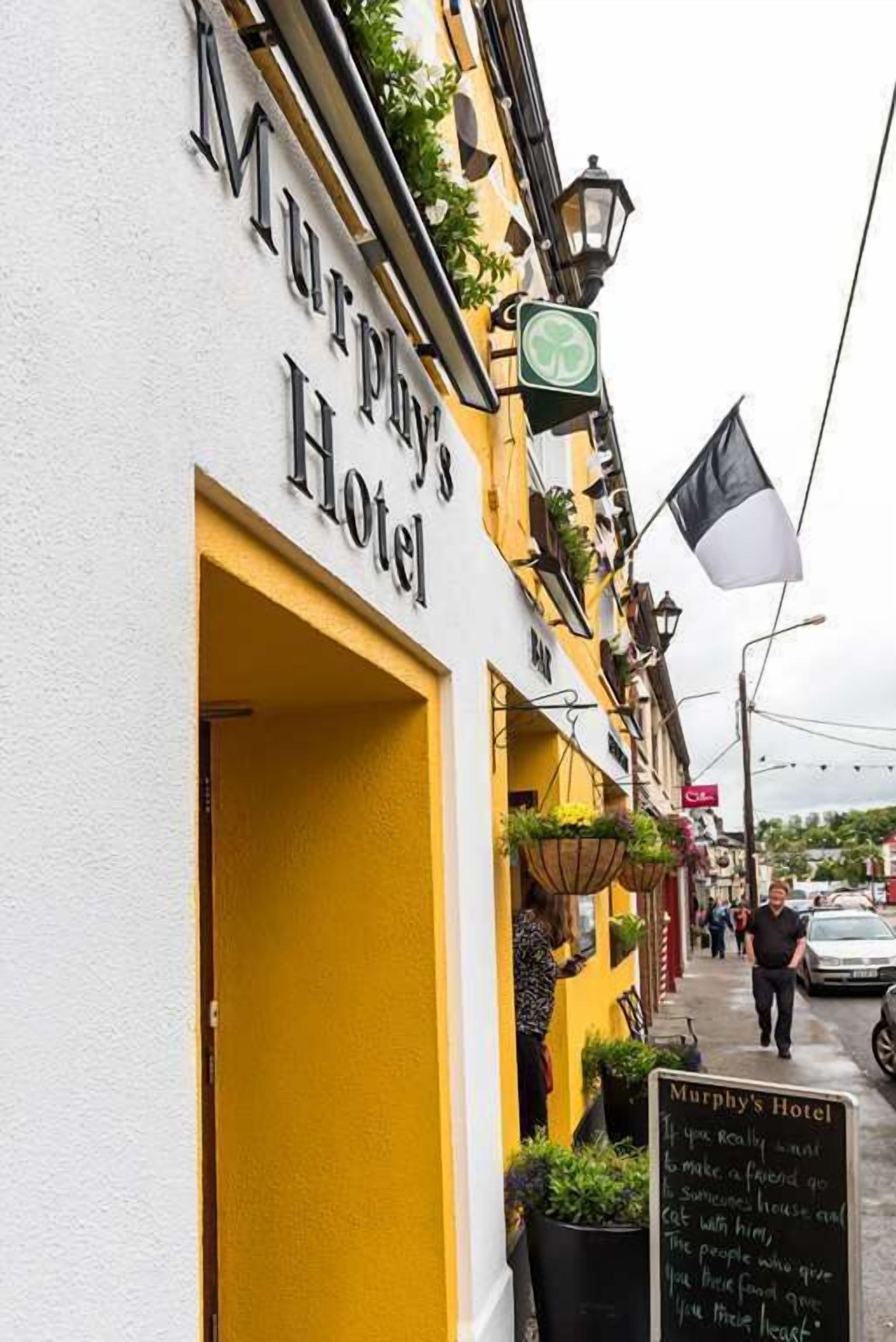 Murphy's Hotel with a yellow facade, a black signboard, and a blackboard with text.