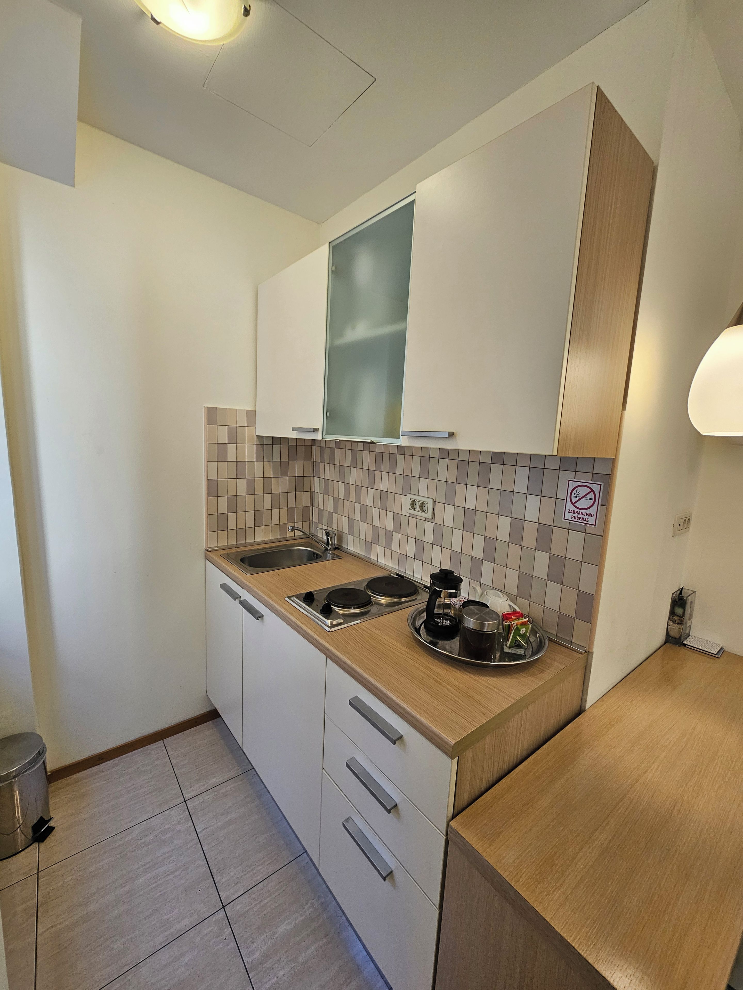 A compact kitchen with a sink, stove, and a tray with a coffee maker.