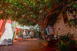 A wooden deck with outdoor seating, surrounded by potted plants and a stone wall.