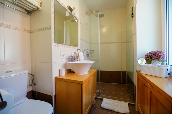 A bathroom with a toilet, sink, shower, and vanity.