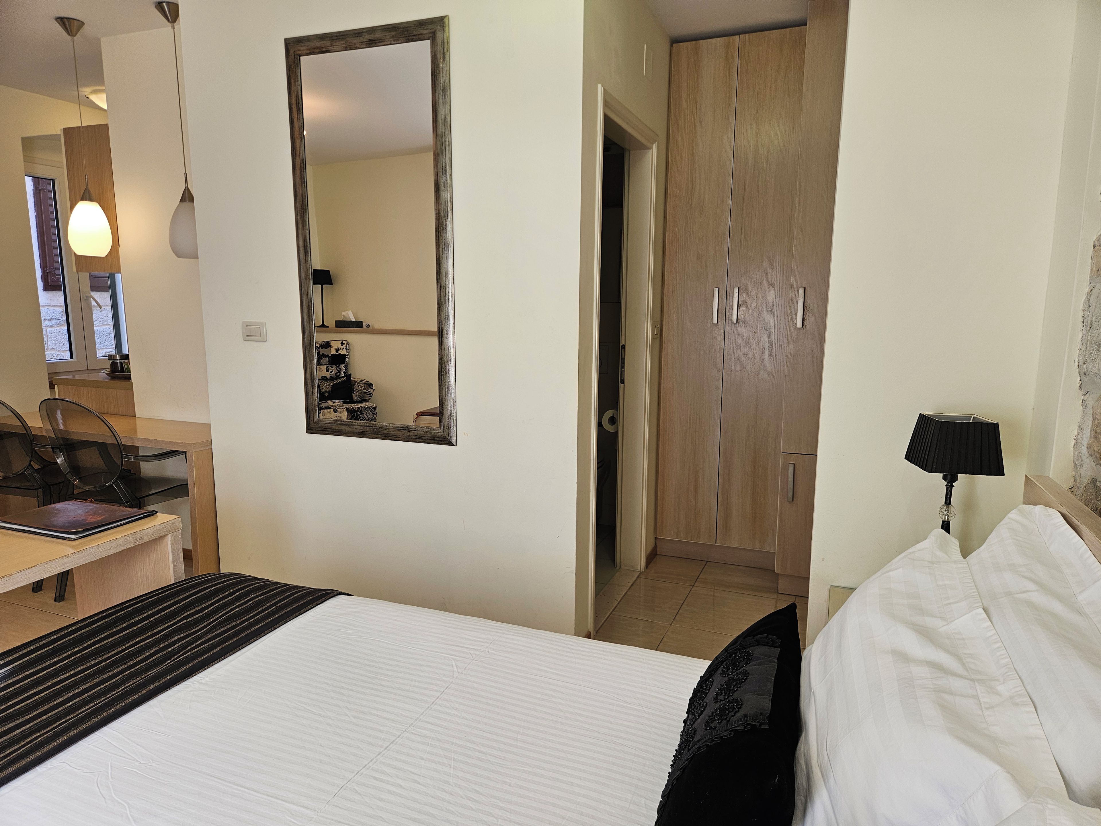 Une chambre d’hôtel comprenant un lit, un bureau, une chaise, une armoire et un miroir.