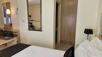 Une chambre d’hôtel comprenant un lit, un bureau, une chaise, une armoire et un miroir.