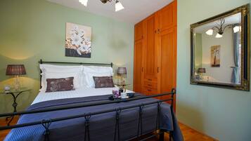 Een slaapkamer met een bed, nachtlampjes, een nachtkastje, een spiegel en een garderobe.