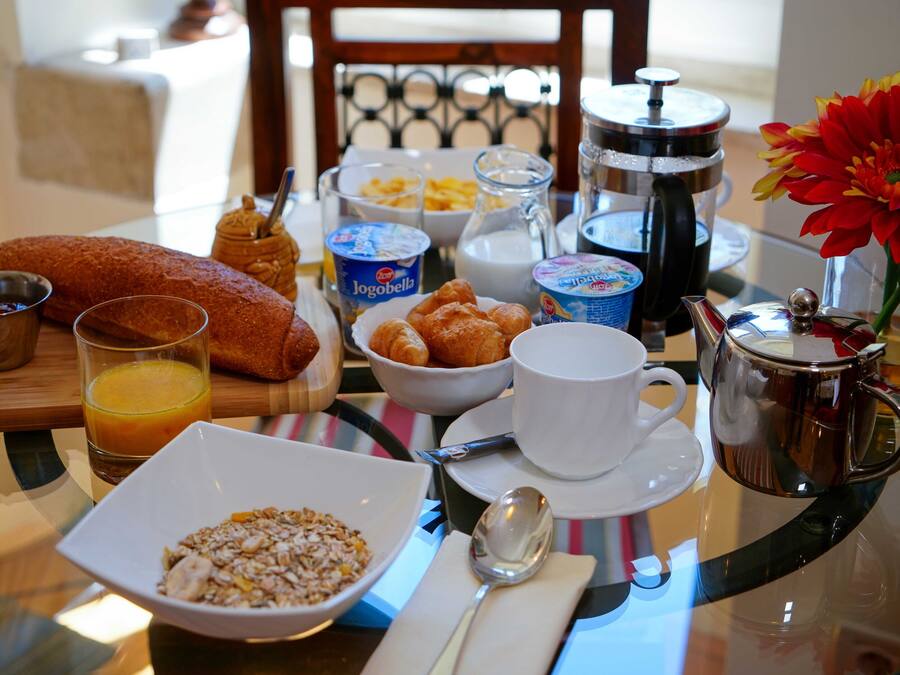 Una mesa de desayuno con croissants, cereal, café y jugo.