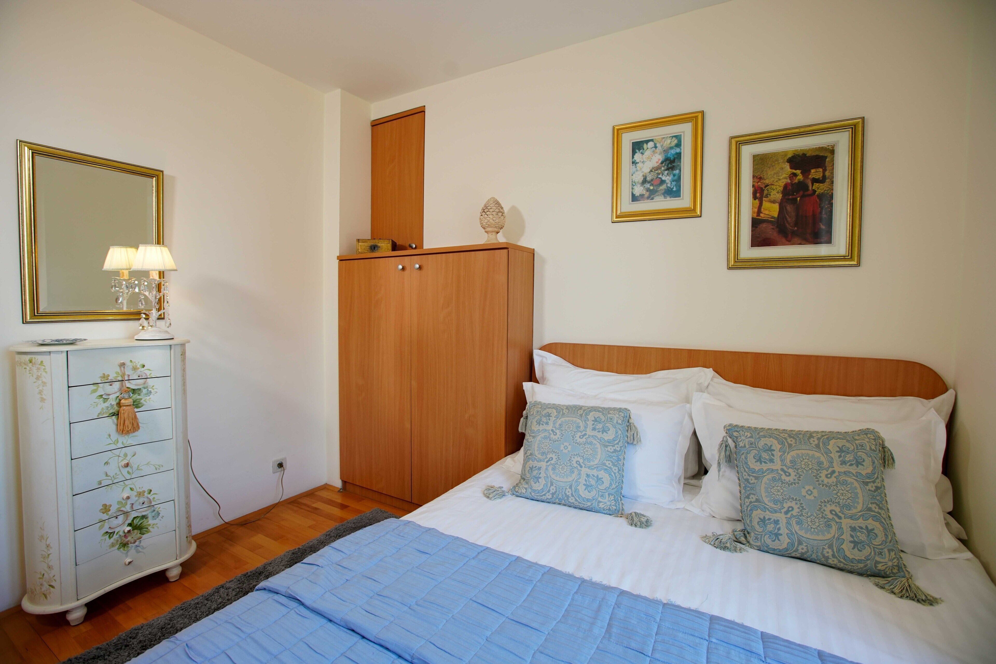 Un dormitorio con cama, cómoda y dos cuadros en la pared.