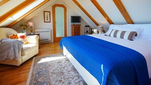 Un dormitorio con una cama grande, un sofá, un televisor y una chimenea.