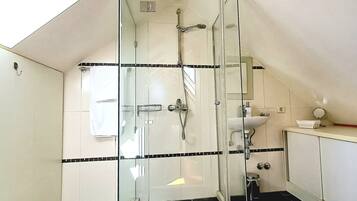Une salle de bain moderne dotée d’une douche à parois de verre, de toilettes et d’un lavabo.
