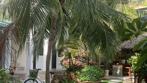 A courtyard with palm trees, a bicycle, and potted plants. - Duy An Guest House (Mui Ne)