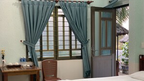 A bedroom with a bed, a wooden desk, a chair, and a window with curtains. - Duy An Guest House (Mui Ne)