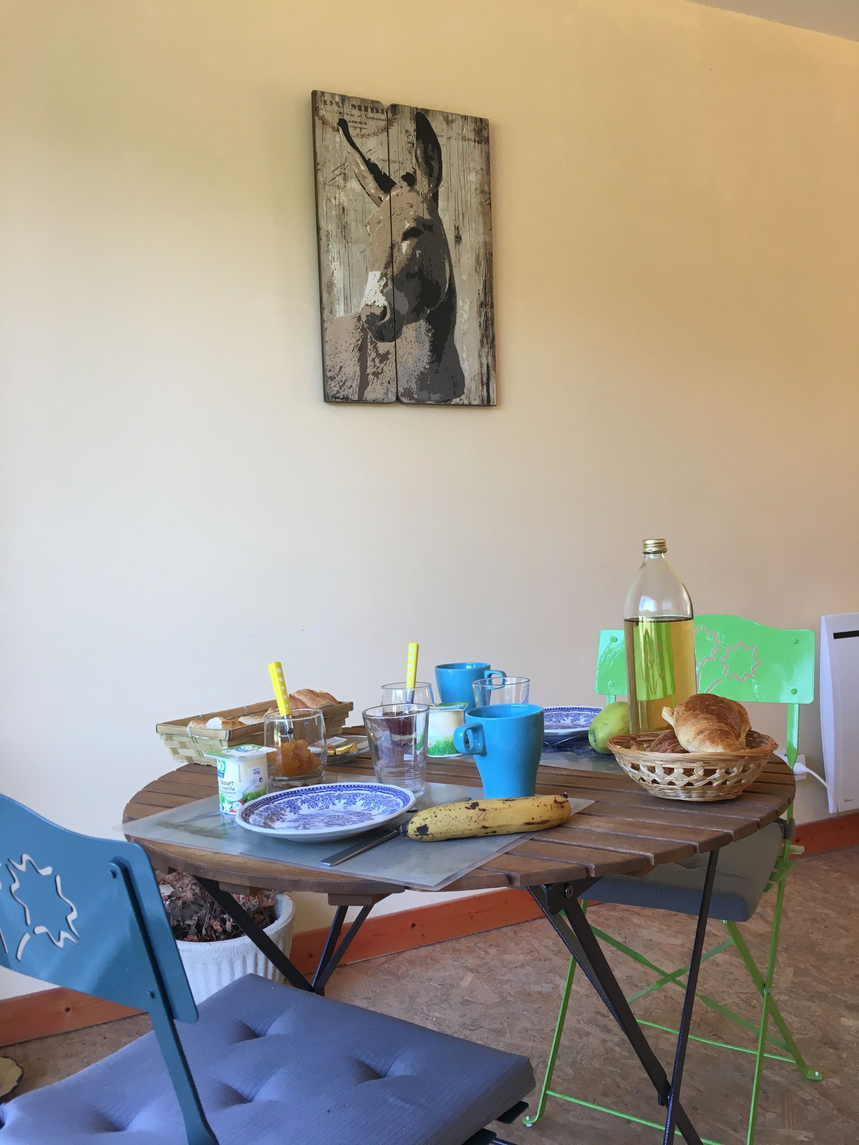 A dining table with a rustic wooden top, surrounded by chairs, and a wall-mounted painting.