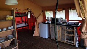 A compact kitchen with a refrigerator, microwave, and stove, a bunk bed, and a hanging light fixture. - Les Ânes de Forcalquier (Forcalquier)