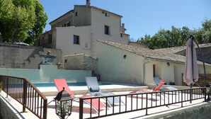 A pool area with lounge chairs and a stone wall. - Les Ânes de Forcalquier (Forcalquier)