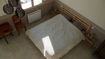 Un dormitorio con una cama, una silla, una mesita y un radiador.