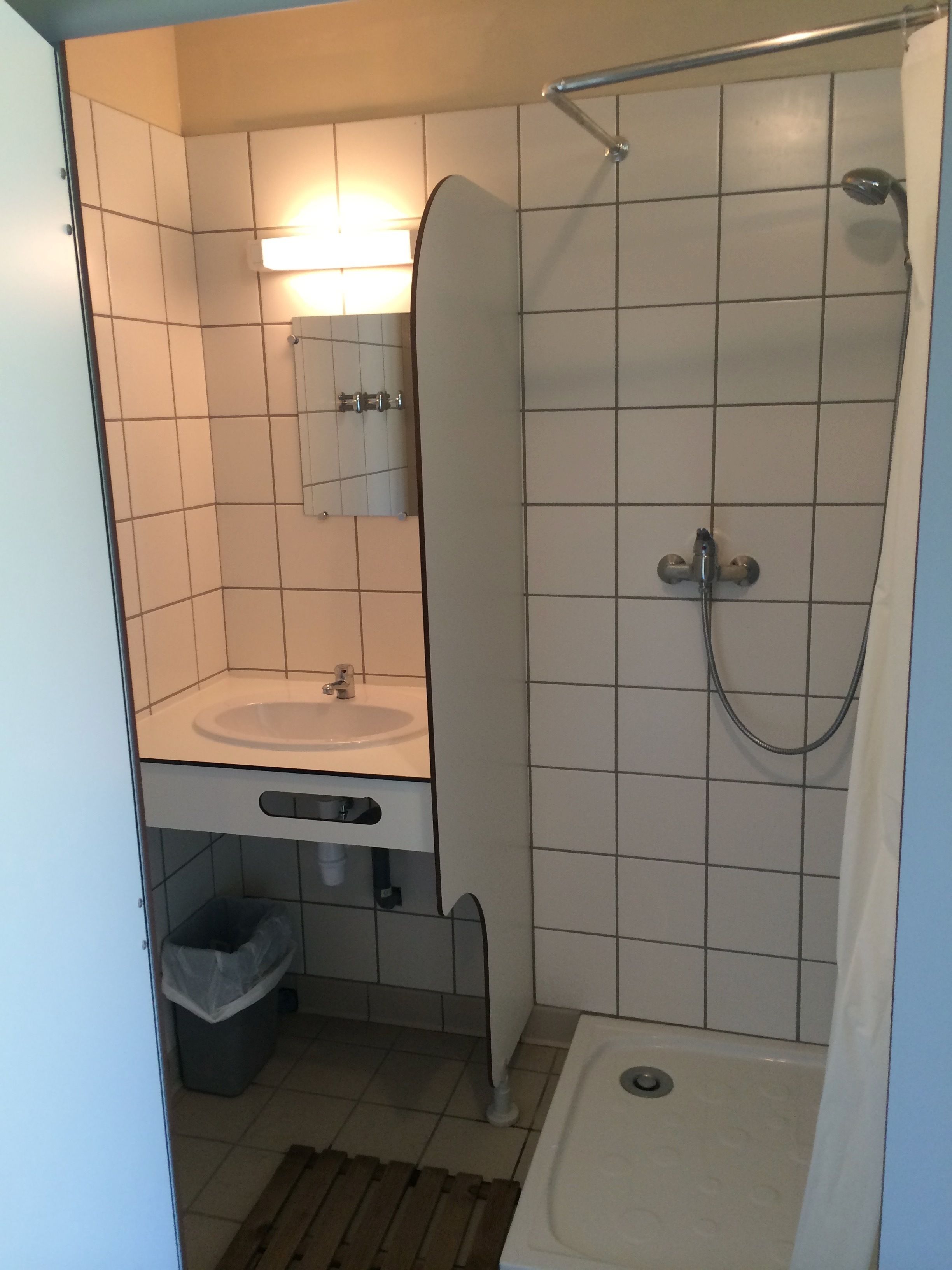 A small bathroom with a sink, mirror, and shower.