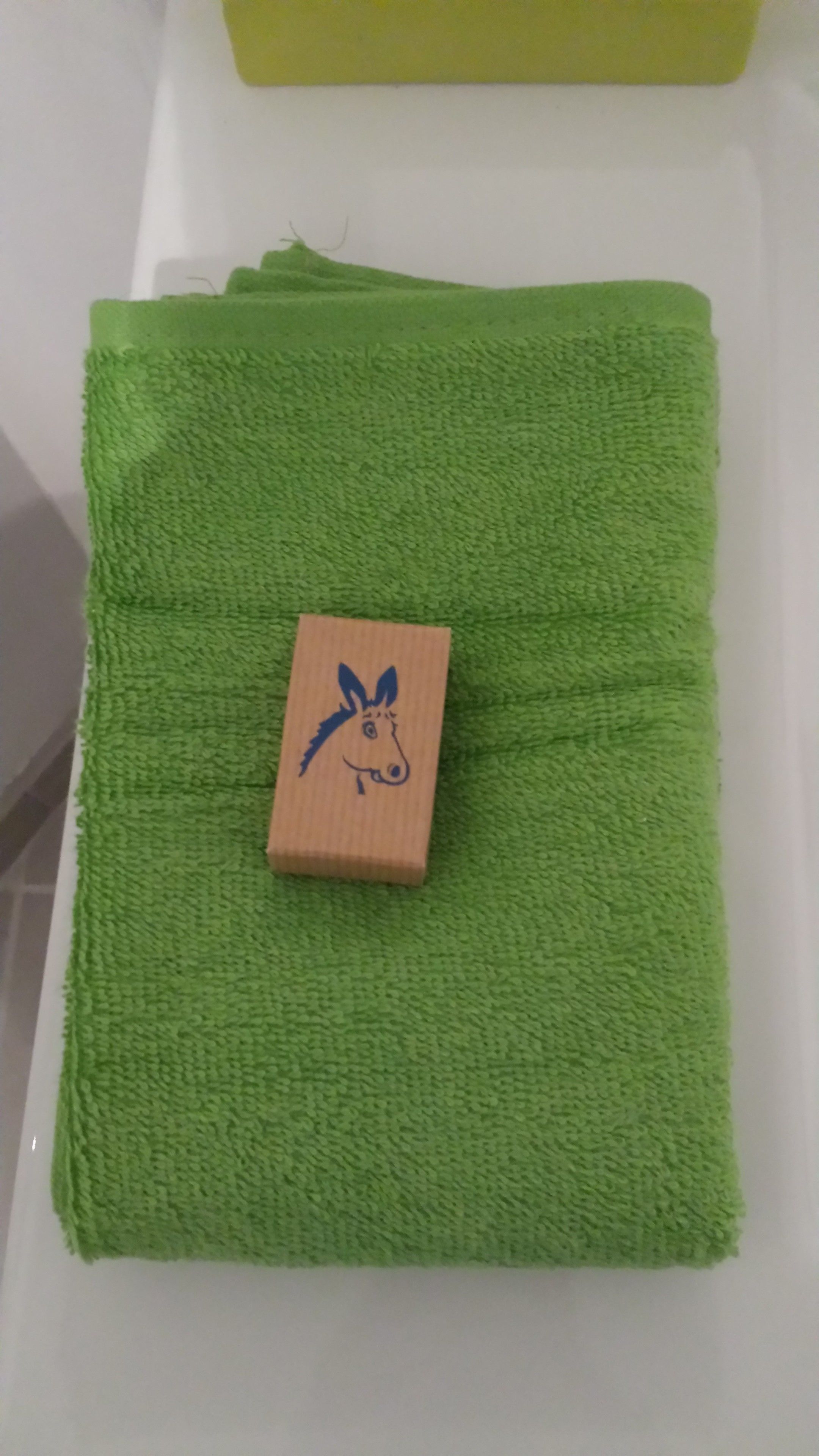 A green towel with a wooden block featuring a donkey's head.