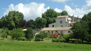 A large, white building with a tiled roof, surrounded by lush greenery and trees. - Les Ânes de Forcalquier (Forcalquier)