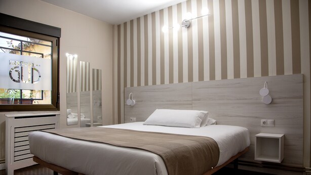 Une chambre moderne avec un grand lit, une tête de lit en bois, des tables de chevet et une fenêtre donnant sur un beau paysage.