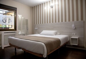 Une chambre moderne avec un grand lit, une tête de lit en bois, des tables de chevet et une fenêtre donnant sur un beau paysage.