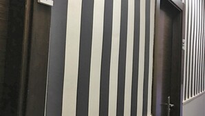 Un couloir avec des panneaux muraux à rayures et une porte dotée d’une poignée.