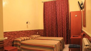 A bedroom with two beds, a wooden nightstand, a chair, a wardrobe, and a radiator. - Cristina Rooms (Rome)