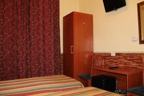 A hotel room with a bed, a desk, a chair, and a television on the wall. - Cristina Rooms (Rome)