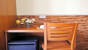A wooden table with a vase of flowers, a chair, and a small black appliance. - Cristina Rooms (Rome)