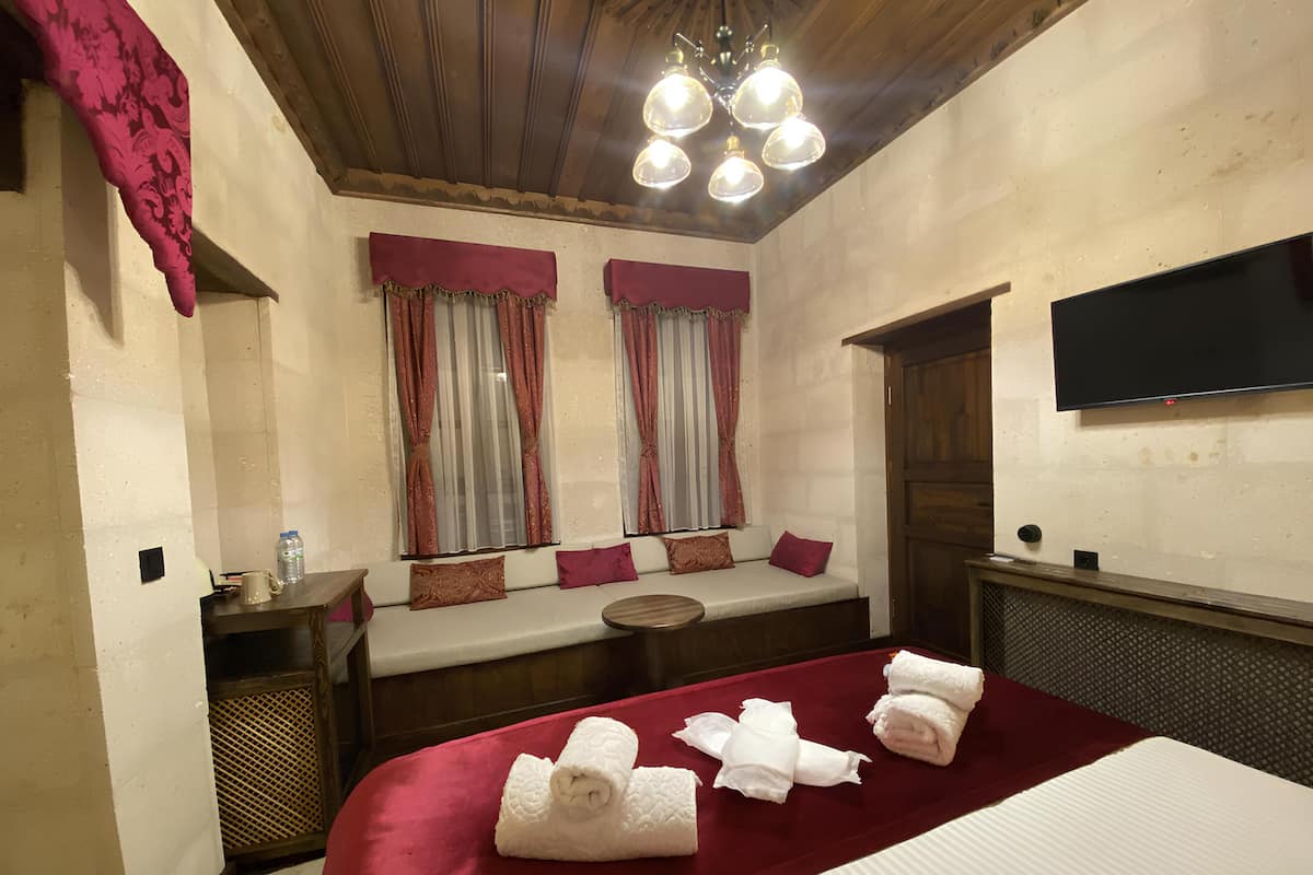 A hotel room with a bed, a seating area, a television, and a window with curtains.