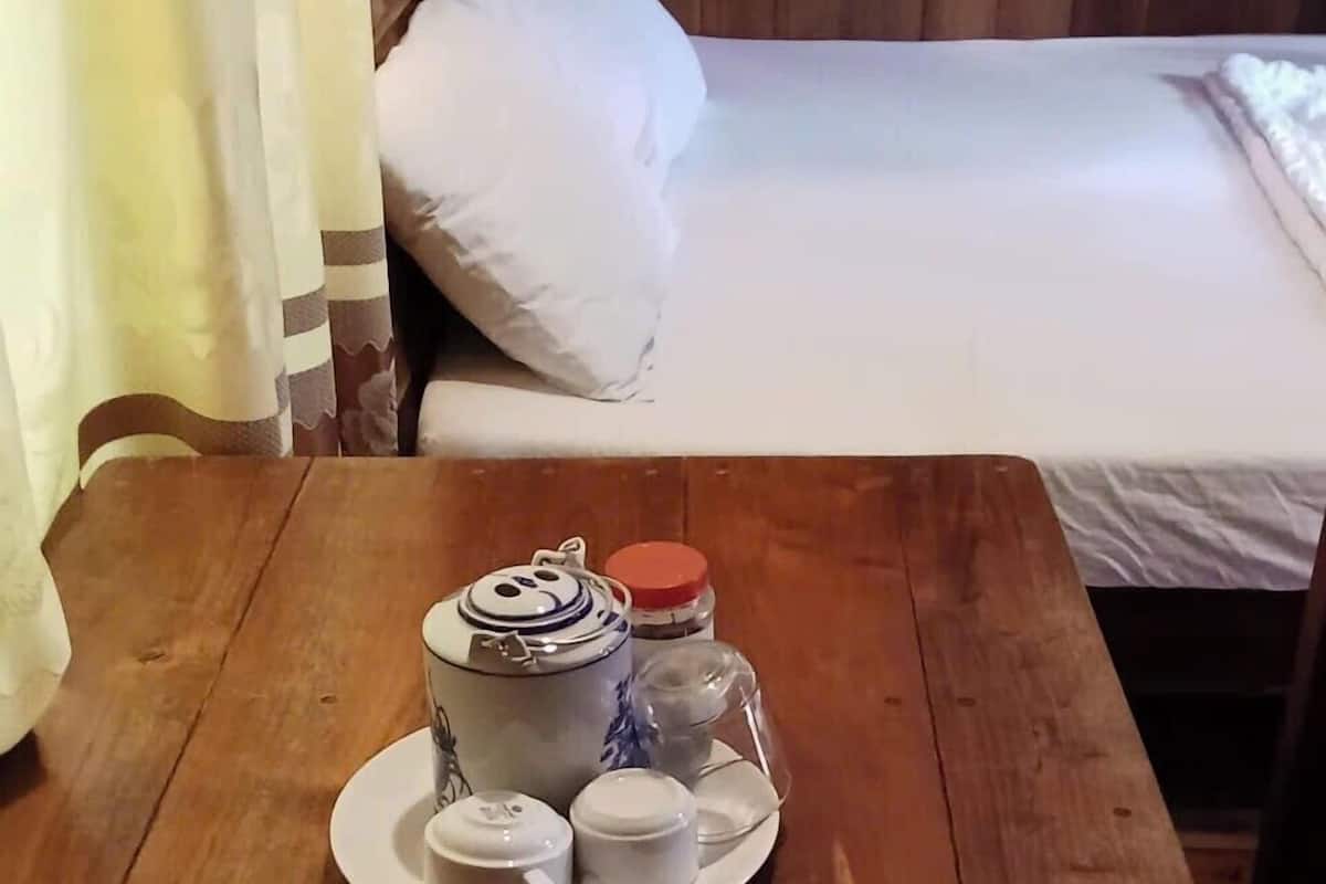 A wooden table with a tray of tea set and a jar of sugar.