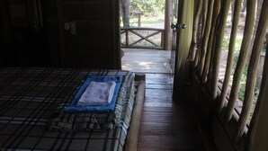 Una cabaña de madera con una cama, una mesita y una puerta que da a un espacio al aire libre.