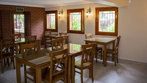A dining area with brick walls, wooden tables and chairs, and large windows with views of greenery. - Ottoman's Pearl Hotel (Istanbul)